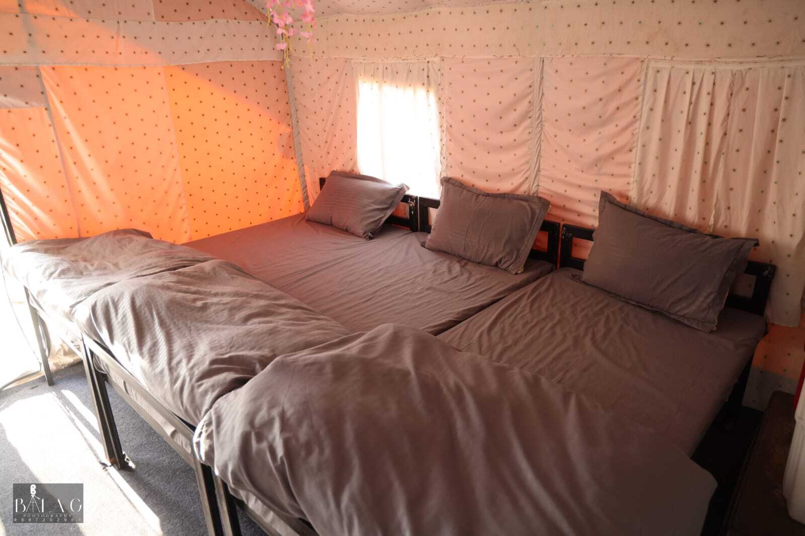 Comfortable bedding setup inside Swiss cottage tent with air cooler at The Jungle Mist Resort
